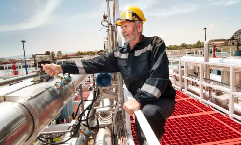 Field worker next to big pipes