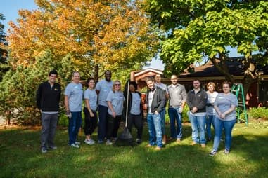 Qualitrol volunteer team gathered outdoors during a community service event in the fall