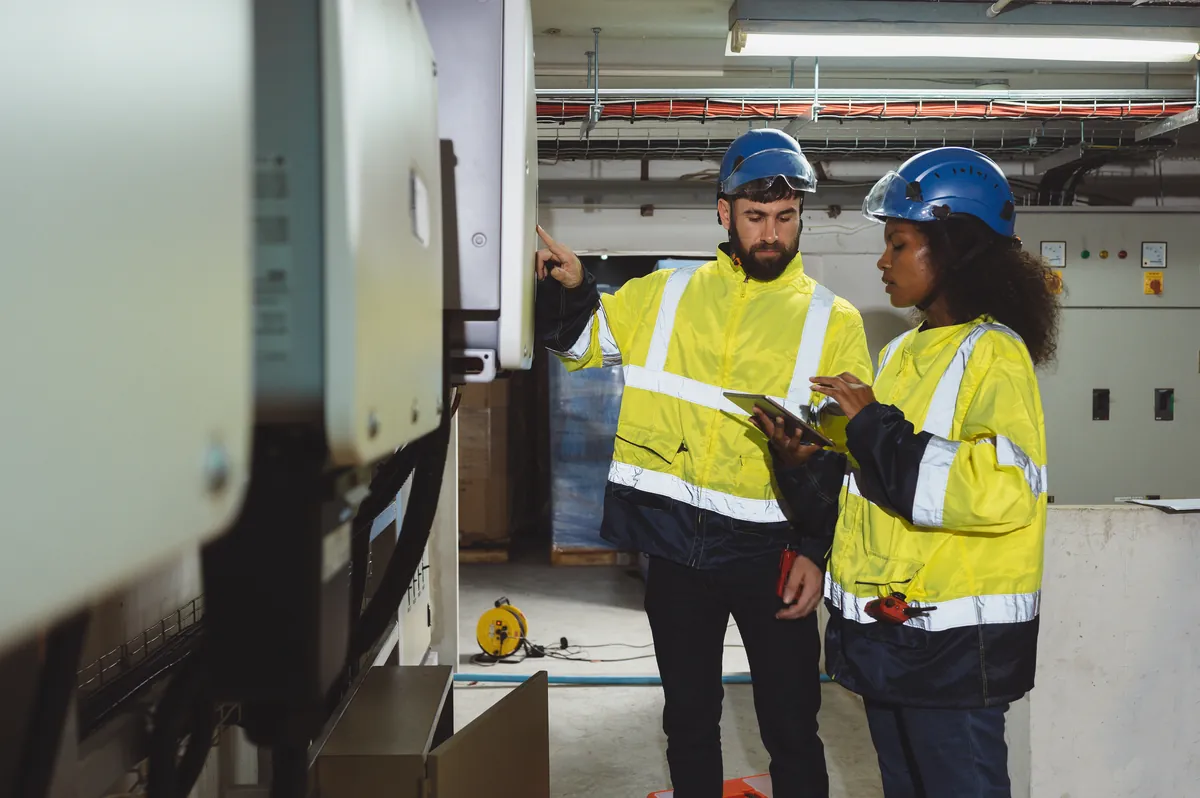 Two industrial workers in PPE reviewing equipment