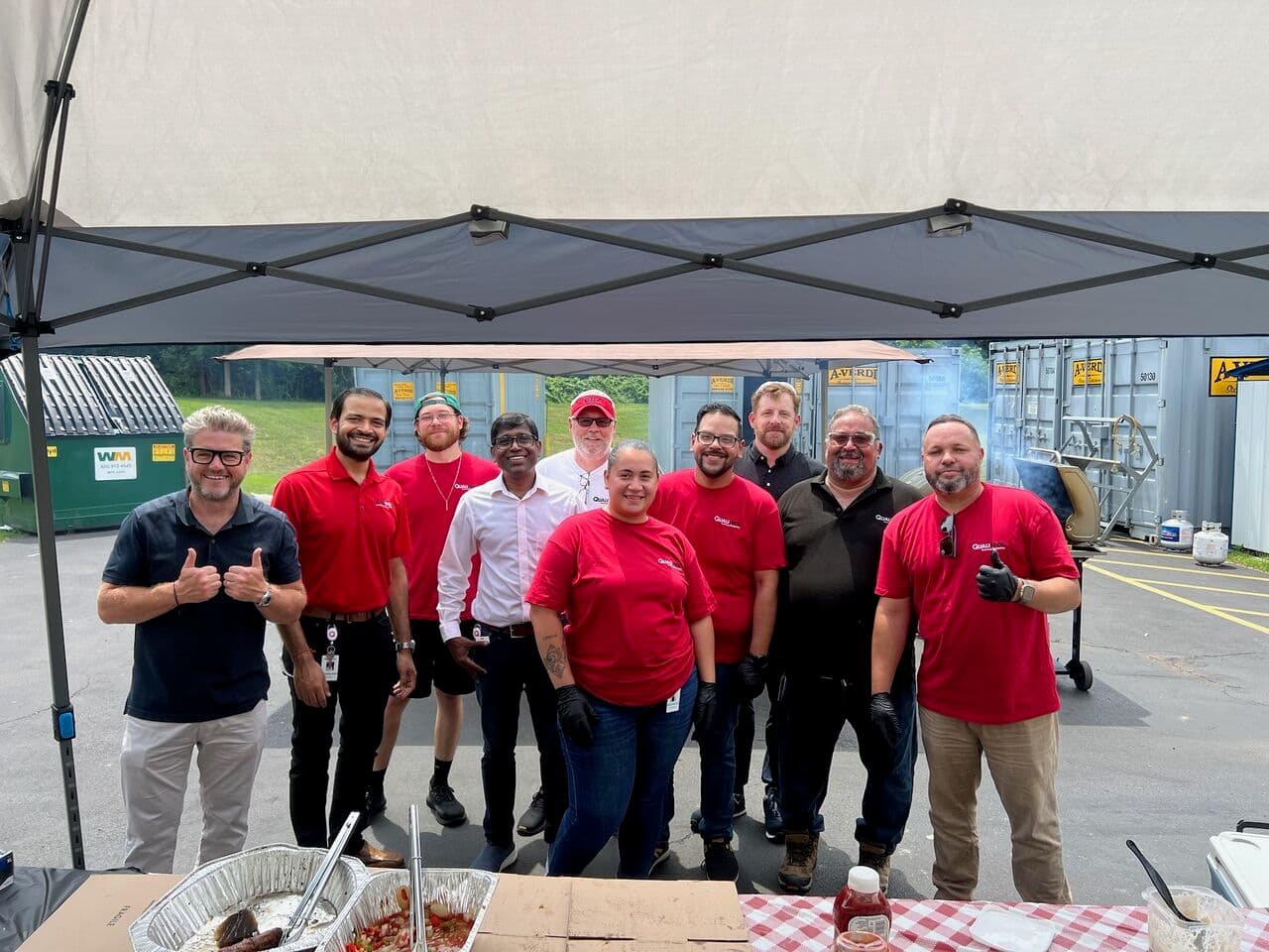 Group of Qualitrol team members in red shirts at company cookout under tent